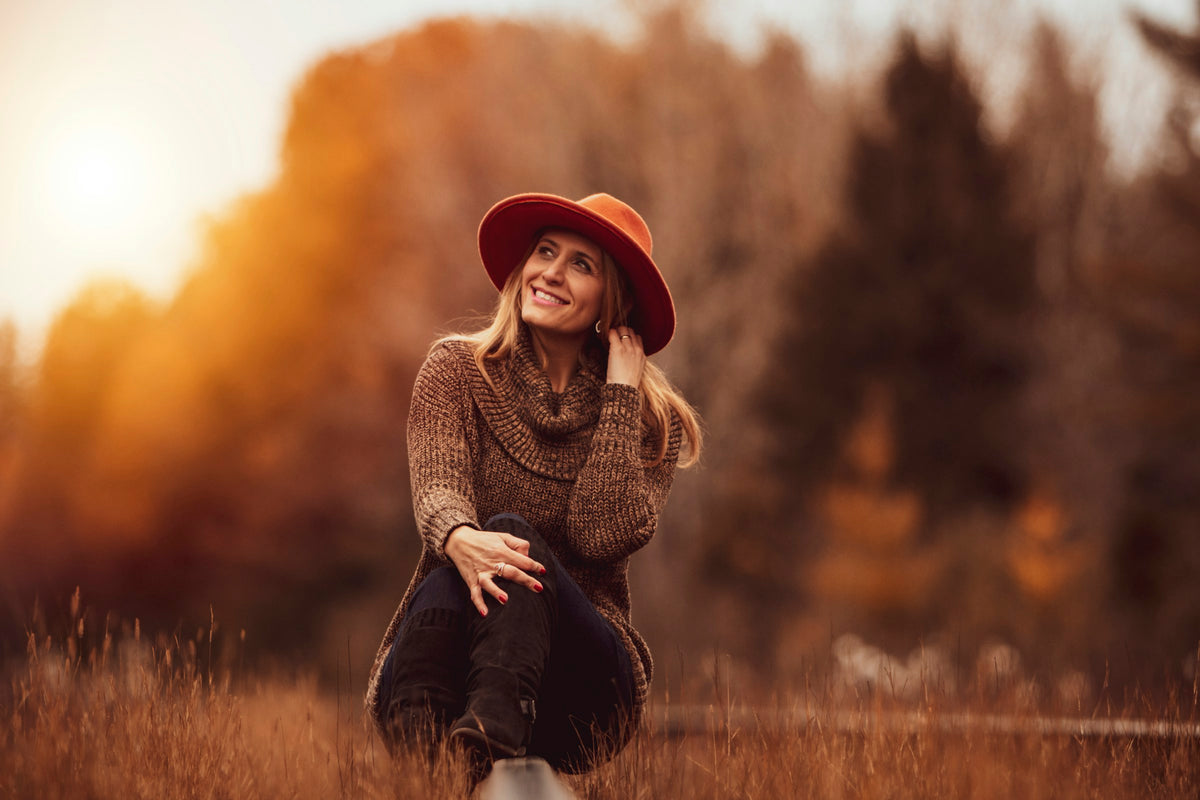 Mulher com camisola de malha num campo de outono